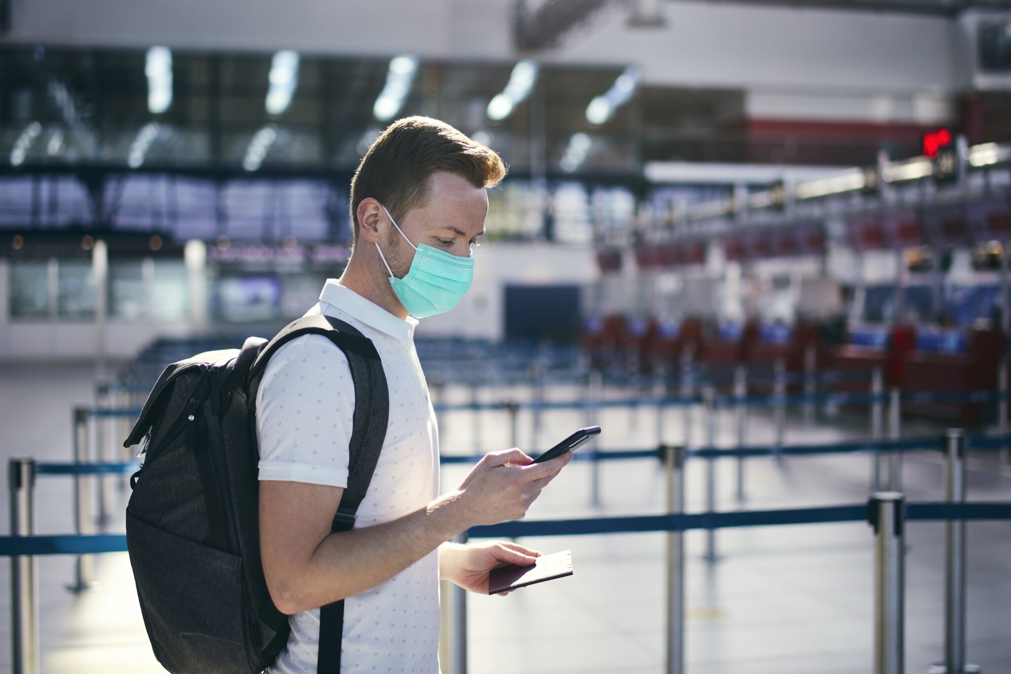 Homem com máscara no aeroporto e a usar uma app no telefone