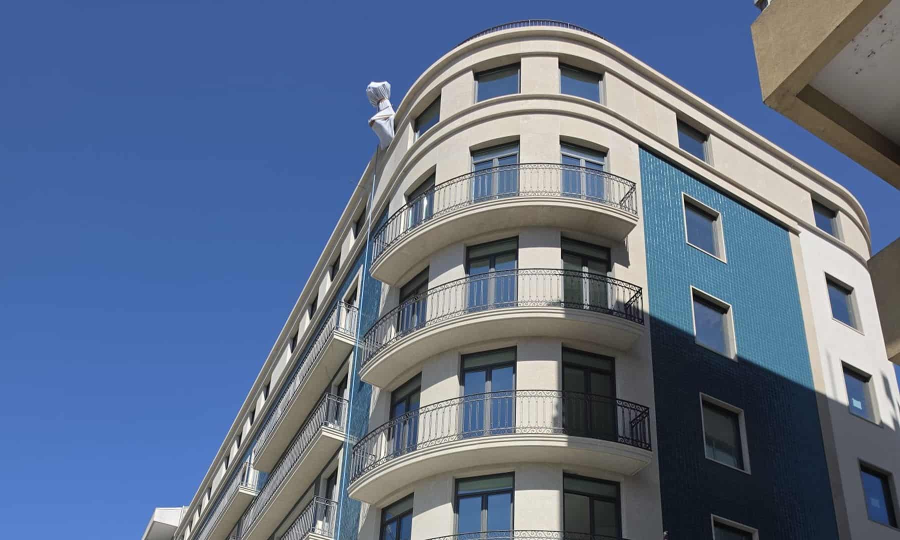 Edifício contemporâneo com varandas e fachada azul em Lisboa.